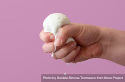 Squeezing mozzarella ball in hand, close up on a purple background 0P7vOb