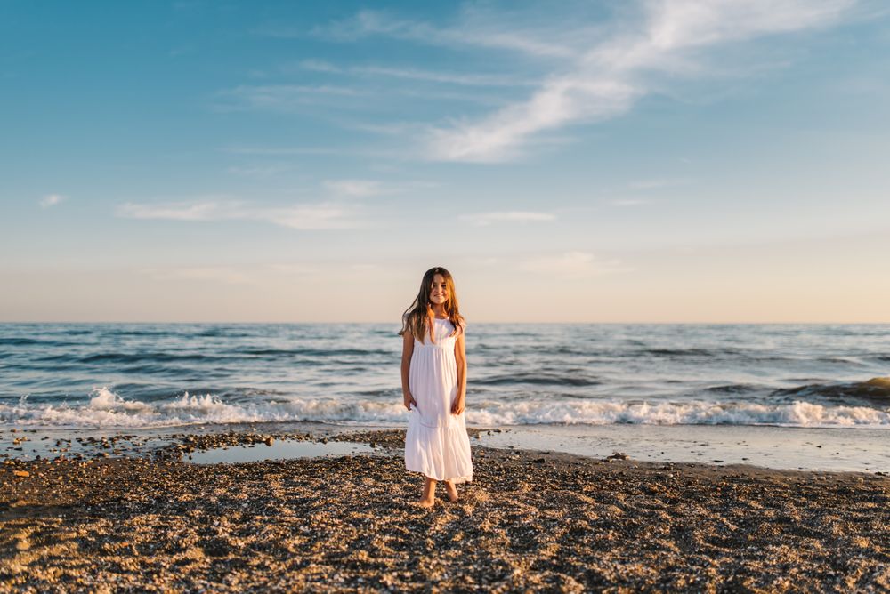 Smiling girl standing on seaside among waves