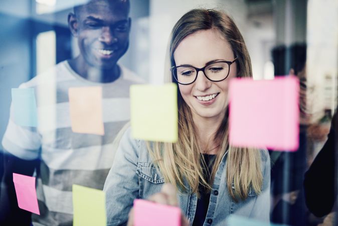 Multi-ethnic colleagues smiling as they brain storm with sticky notes