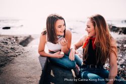 Two young women talking on the beach QbDjp5