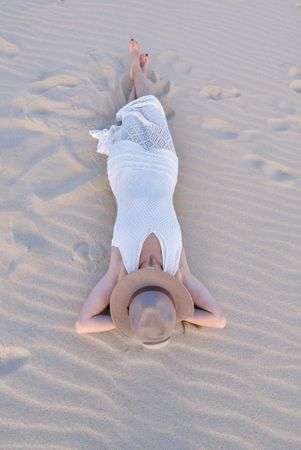 Woman in white dress relaxing on sand