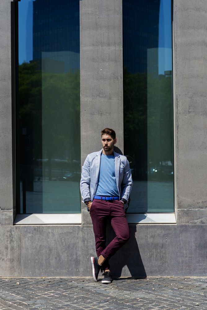 Man leaning on wall outside in the sun, vertical