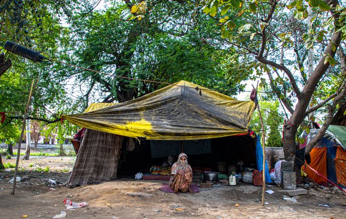 Older woman sitting outside makeshift tent in India