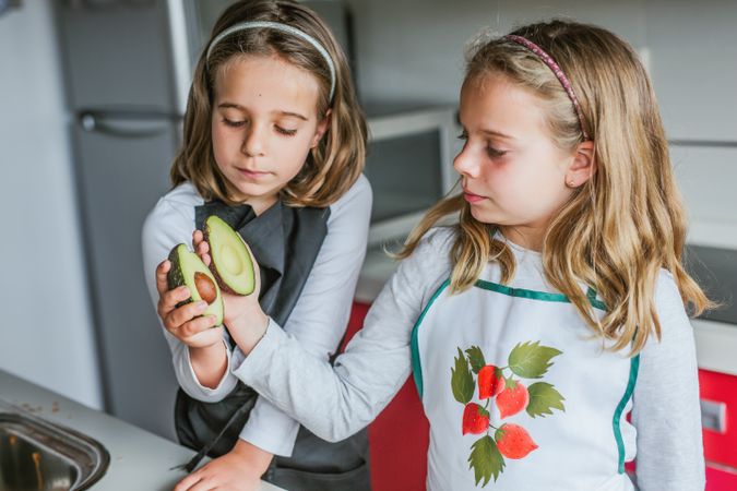 Little girls looking at cut avocado