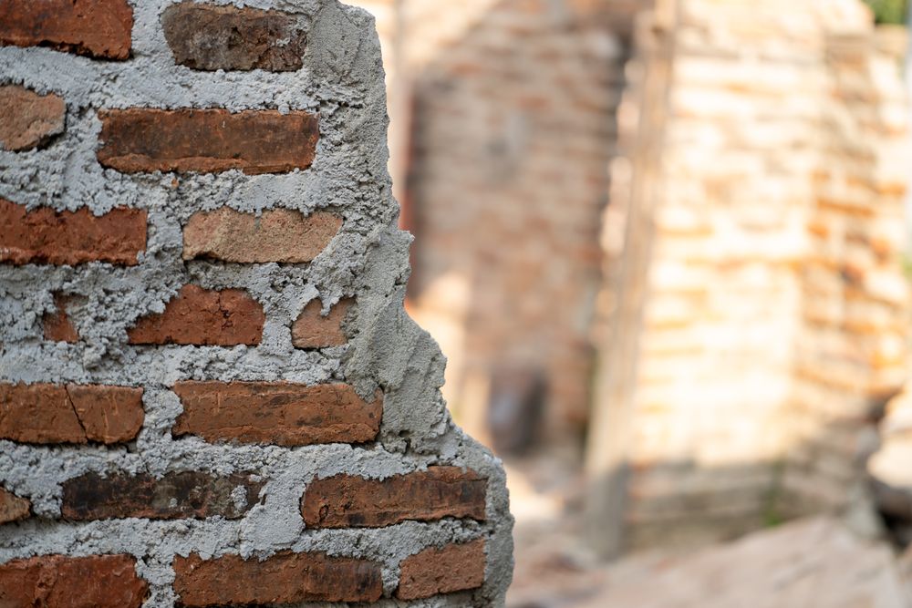 Half-collapsed brick wall with rough unfinished cement