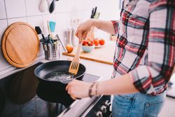 Woman standing over a stove pre-heating a pan