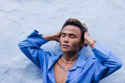 Asian male in blue shirt running hands through his hair