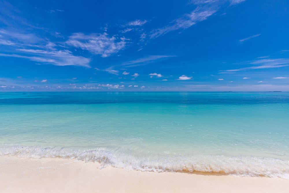 Blue waves coming in on a beach in the Maldives