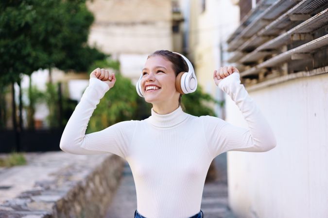 A Joyful and Carefree Young Woman Joyfully Enjoying Music While Outdoors in Daylight