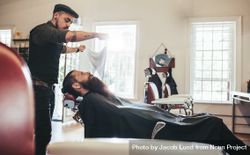 Barber applying towel to customer lying down in chair 47r2B5