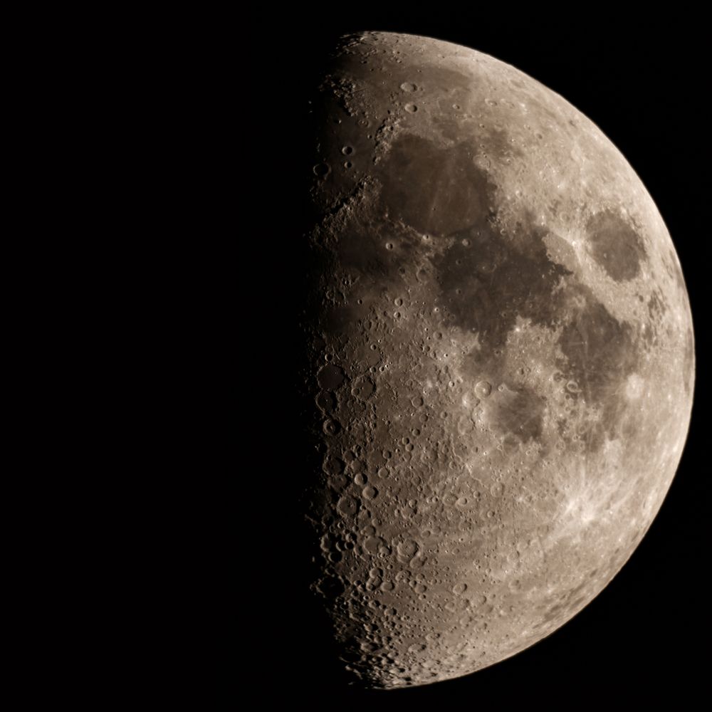 First quarter moon with detailed craters and rugged surface.