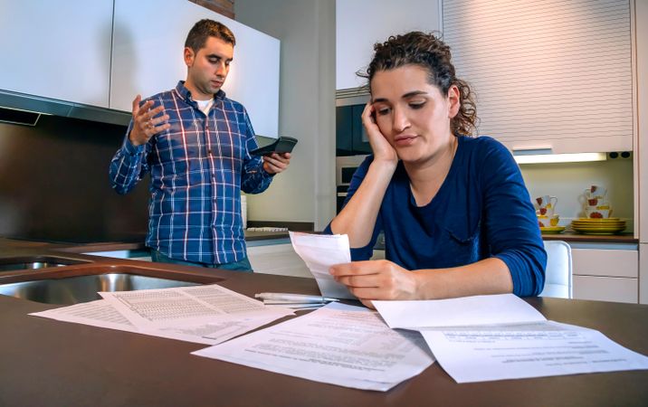 Frustrated couple going through bills in their kitchen
