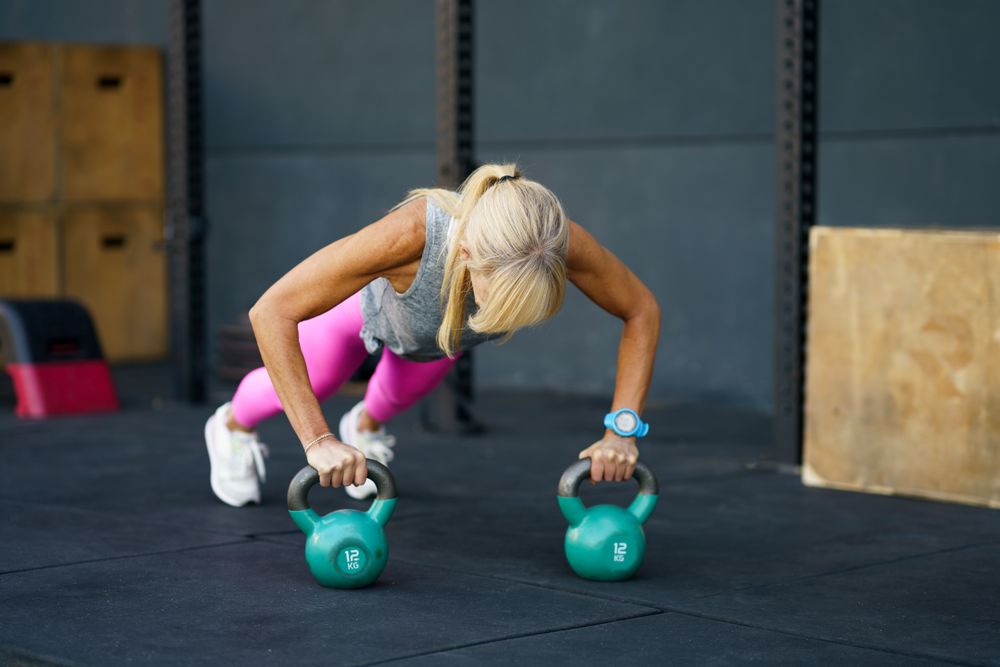 Healthy woman doing pushups with kettle bells