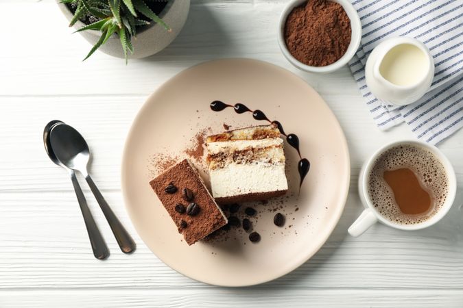 Composition with tasty tiramisu and cocoa drink on light wooden table. Delicious dessert
