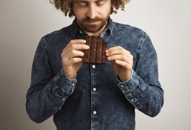 Man looking at chocolate bar he is holding