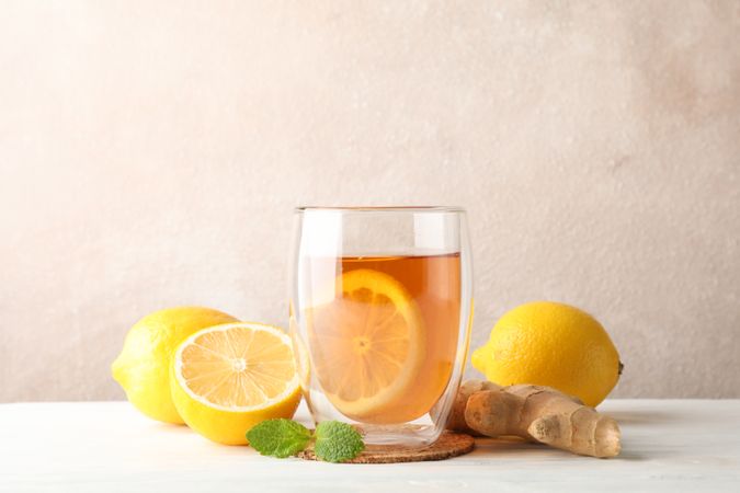 Glass of tea with lemon, mint, honey, dipper and ginger on wooden background ,copy space
