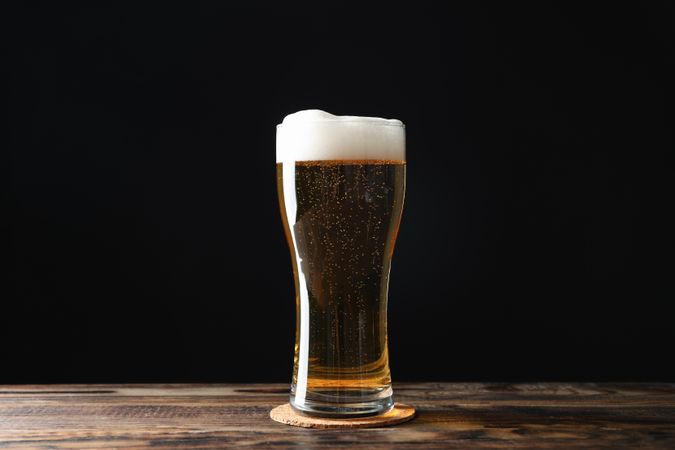 Mug with beer on wooden table, space for text