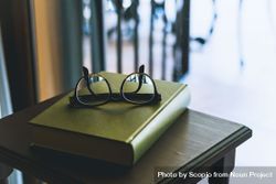 Framed eyeglasses on green book 5QXAX0