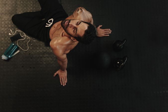 Exhausted man relaxing on gym floor after workout