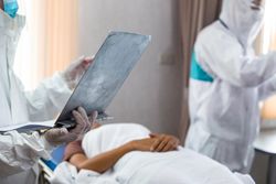 Emergency paramedic doctor in PPE suit hand holding report clipboard