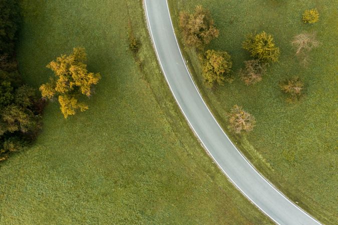 Drone shot a curved road passing through green meadow