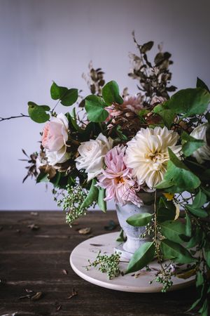 Composition of flowers and plants in vintage vase on board