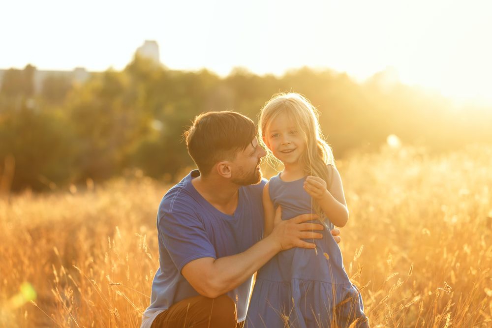 Dad and daughter sitting in field of long grass