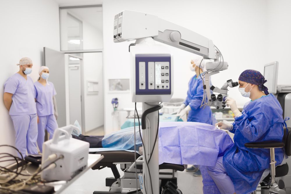 Doctor looking through eye equipment while in surgery with team