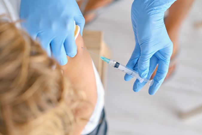 Faceless nurse with syringe vaccinating patient in hospital