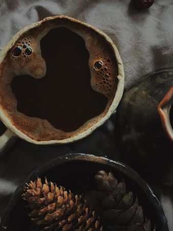 Close up of coffee cup and pinecones on bed