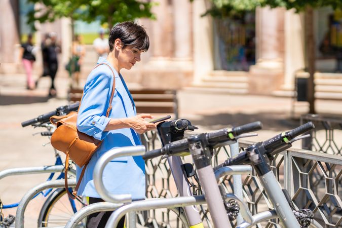 Woman in blue blazer checking phone at bicycle rack