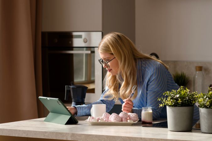 Woman working on tablet in kitchen with breakfast