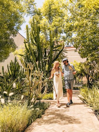 Man and woman walking on pathway near green trees