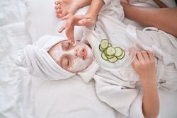 Unrecognizable woman applying facial mask on child
