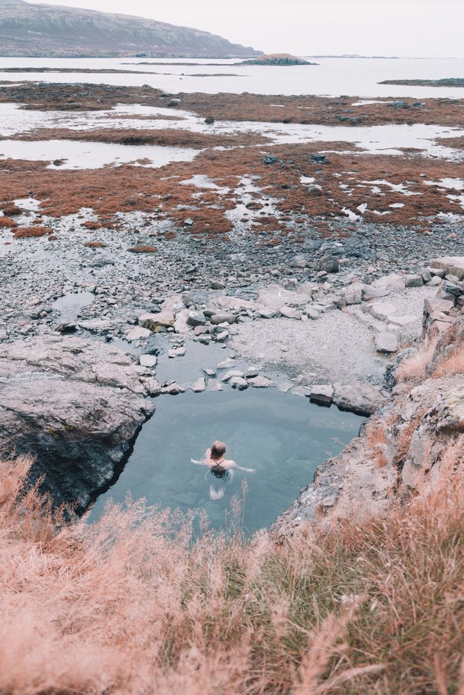Woman in pond near hill on shore