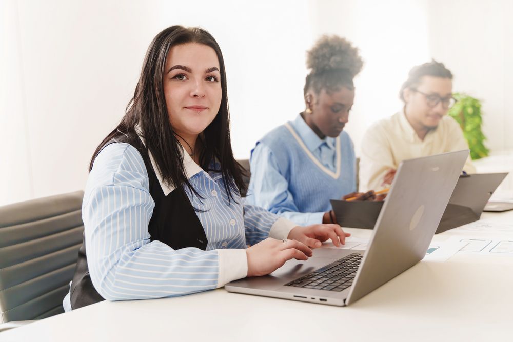 Portrait of woman working on laptop in a diverse office