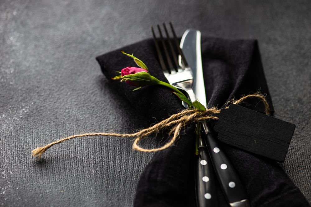 Silverware in matching napkin on counter with copy space and flower