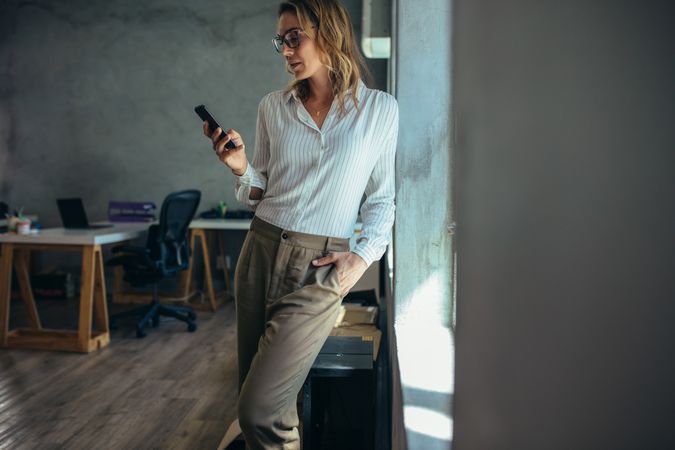 Businesswoman standing in office and using her smart phone