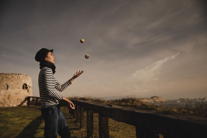 Woman juggling balls on meadow on shore