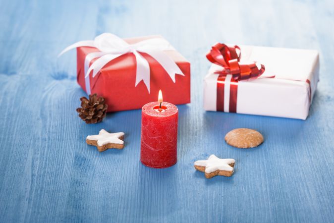 Gifts and red candle on blue table