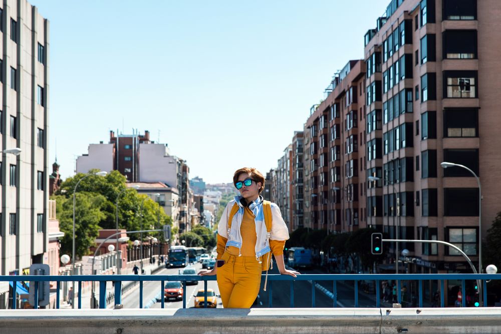 Stylish pensive woman contemplating city while standing on road bridge