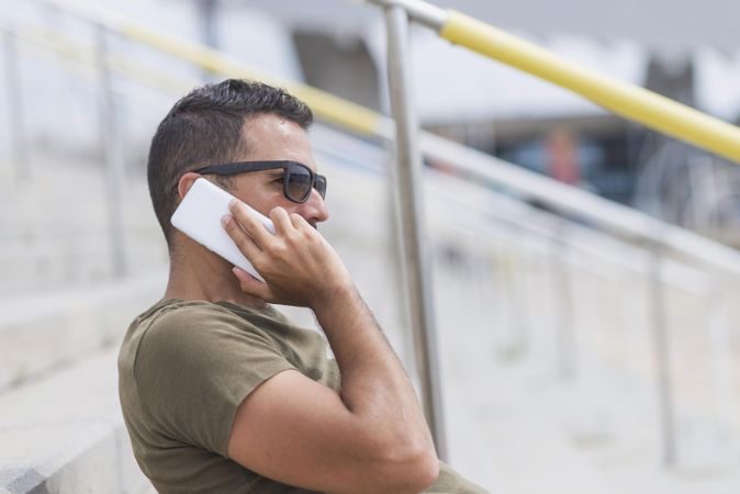 Side view of male sitting on stairs talking on cellphone