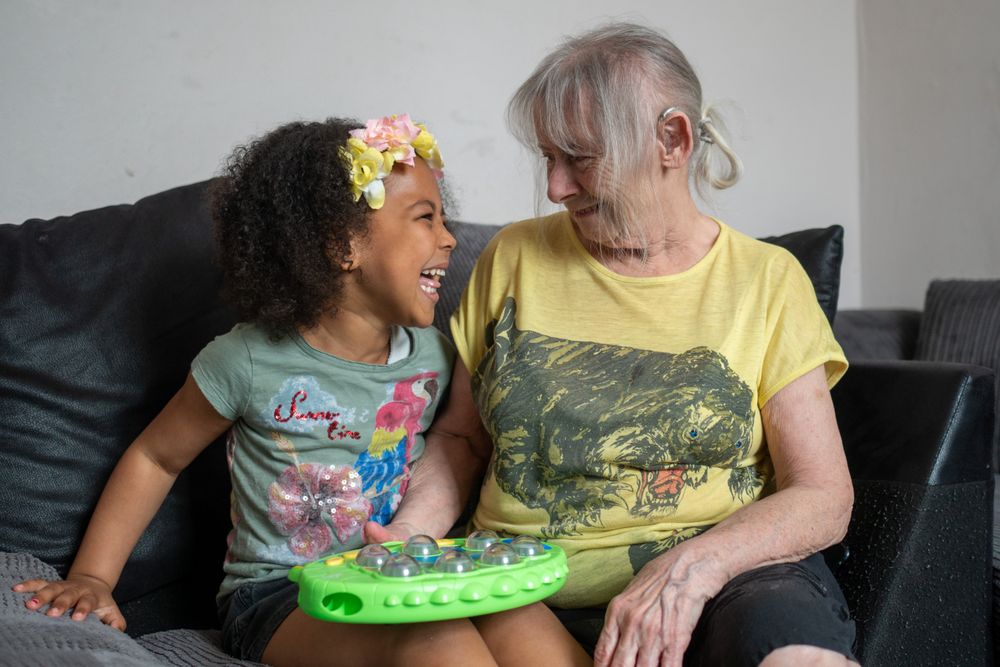 Older woman and grandchild laughing on coach at home