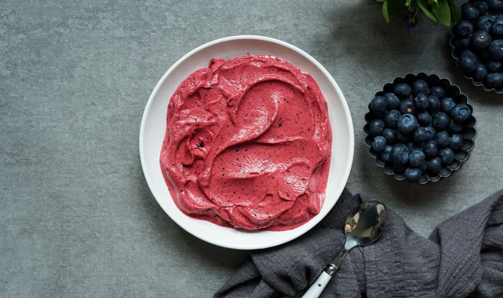 Smoothy of fresh bog blueberries and raspberries in bowl near napkin