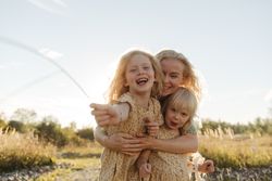 Cheerful mother embracing daughters in countryside