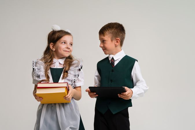 Portrait two elementary school students in uniform with books and tablet pc