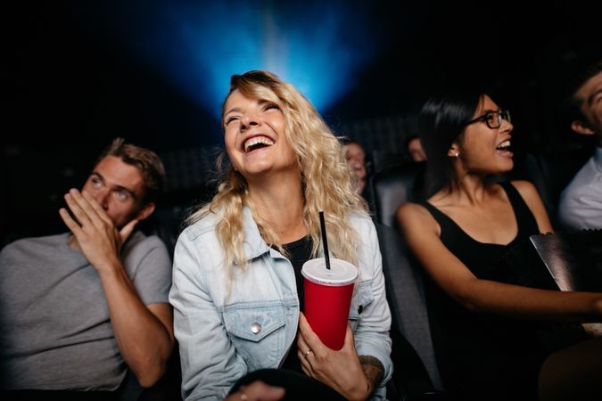 Indoor shot of smiling young woman watching woman in theater