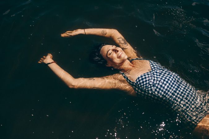 Woman in bikini floating in water facing up