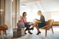 Two women working together with notes and a laptop
