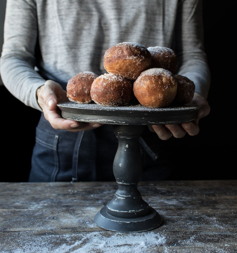 Person near baked cakes on stand on table